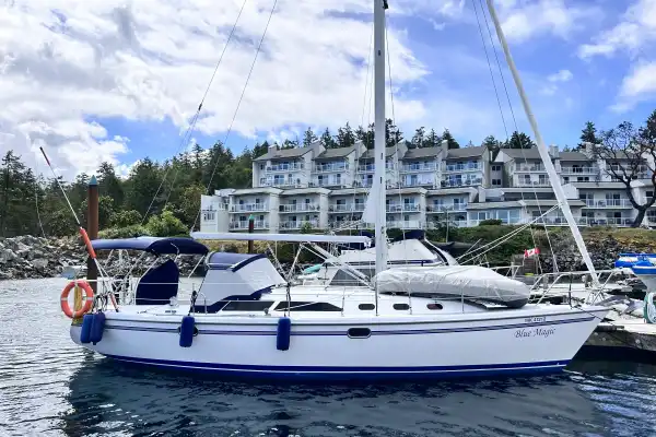 Catalina 34 MKII Seen from the starboard side with bimini, dodger, window covers. In front of the mast is a tender with a cover and three fenders are on the aft end of the boat equally spaced.